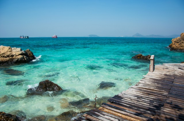 Rocks,And,Wooden,Bridge,On,The,Beach,With,Clear,Sea